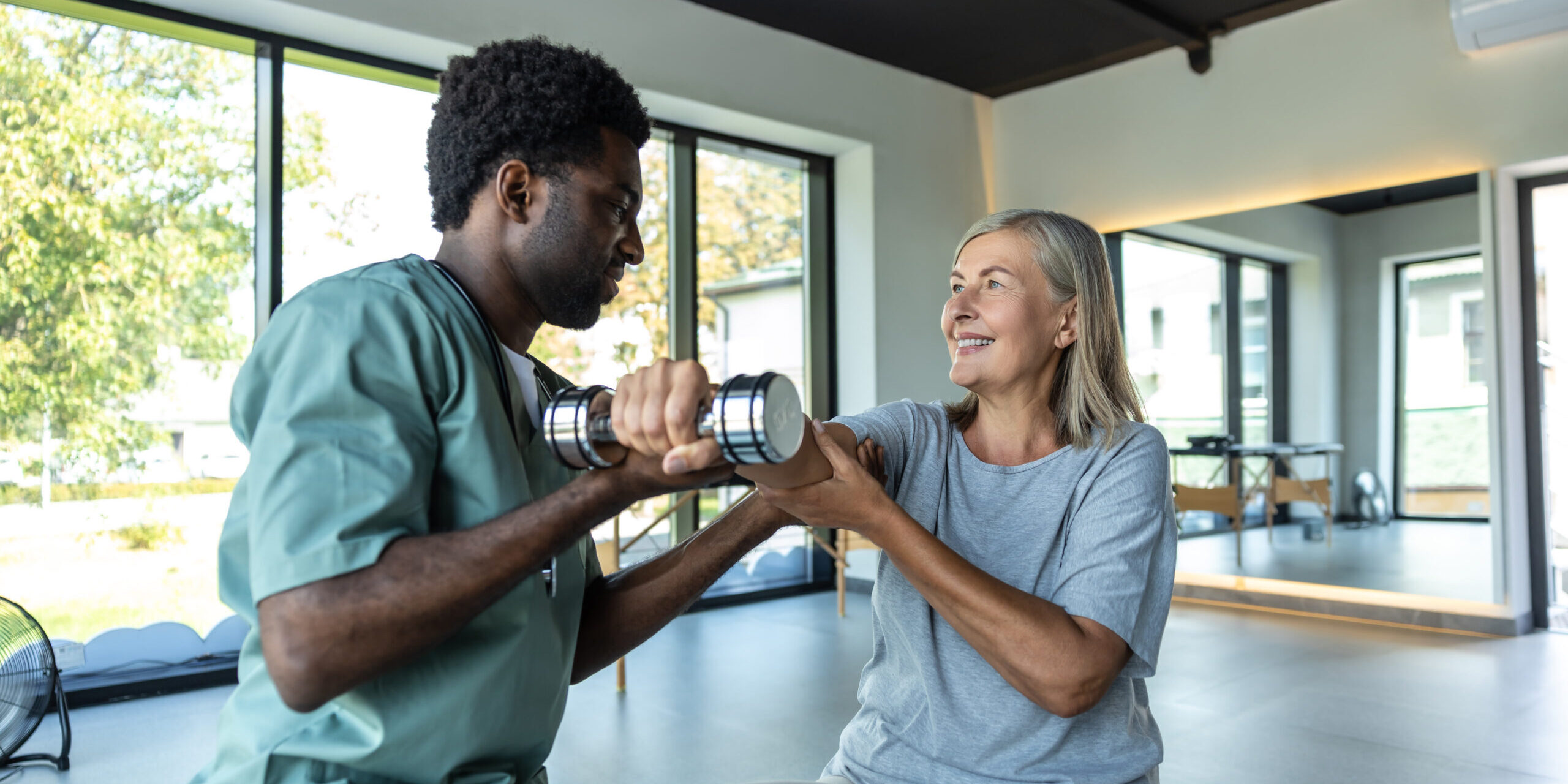 Chiropractor consulting adult patient for recovery after injury through rehabilitation