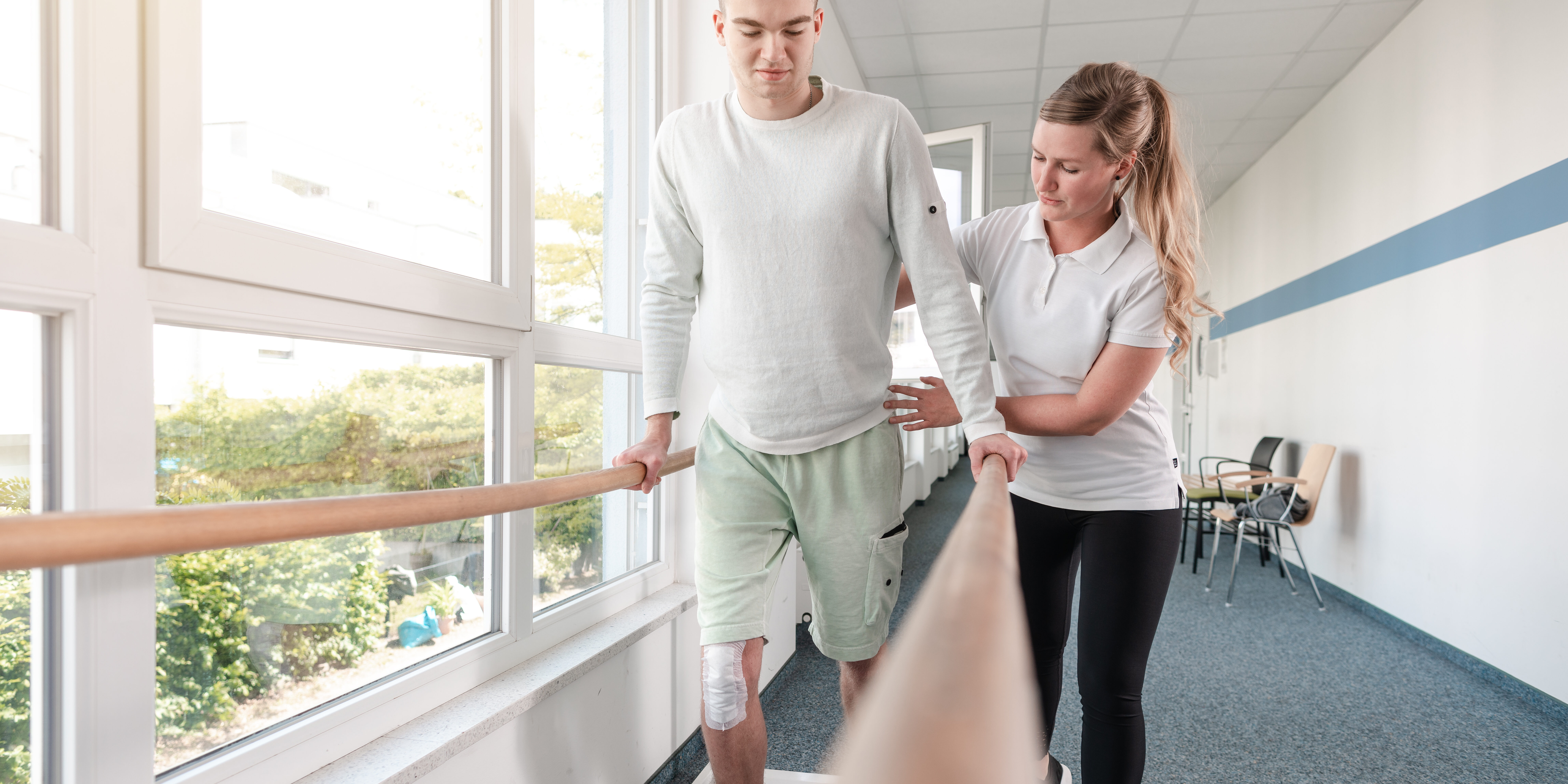 Therapist helping young man learning to walk again in rehabilitation