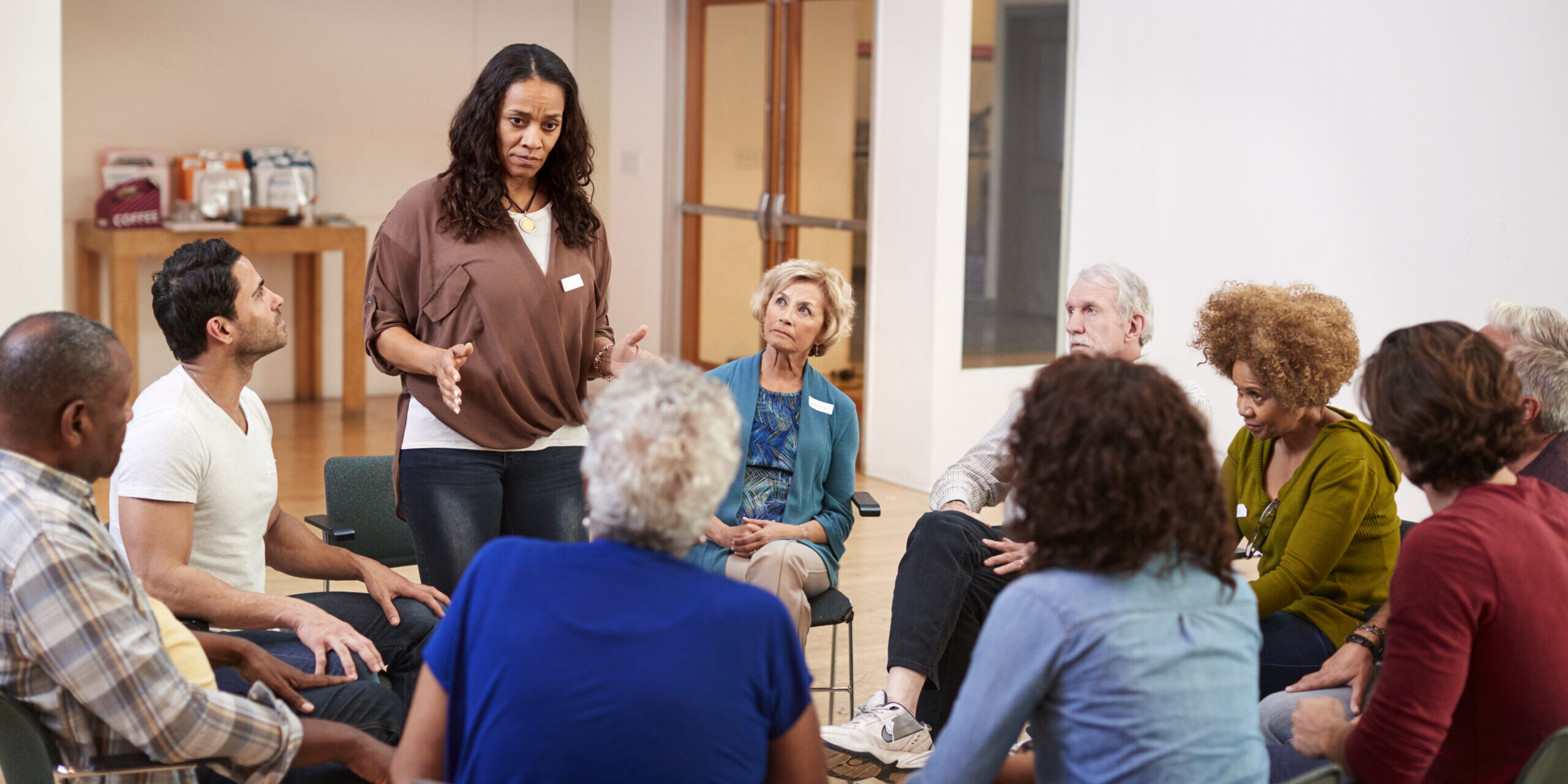Woman Standing To Address Self Help Therapy Group Meeting In Community Center